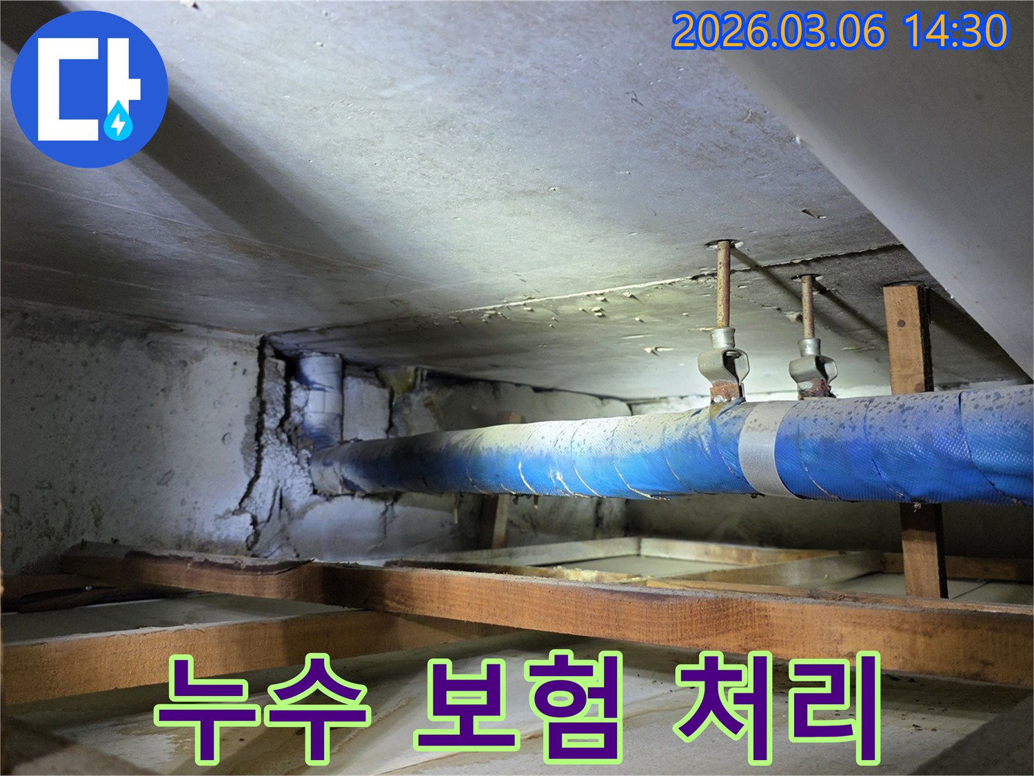 지하 공간의 파란색 배관과-손상된 콘크리트 벽면을-누수 엔지니어가-누수 보험 처리 상담을 위해-점검하는 모습