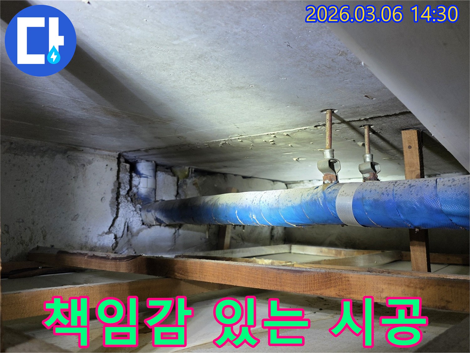 지하 공간의 파란색 배관과-손상된 콘크리트 벽면을-누수 엔지니어가-책임감 있는 시공을 위해-점검하는 모습