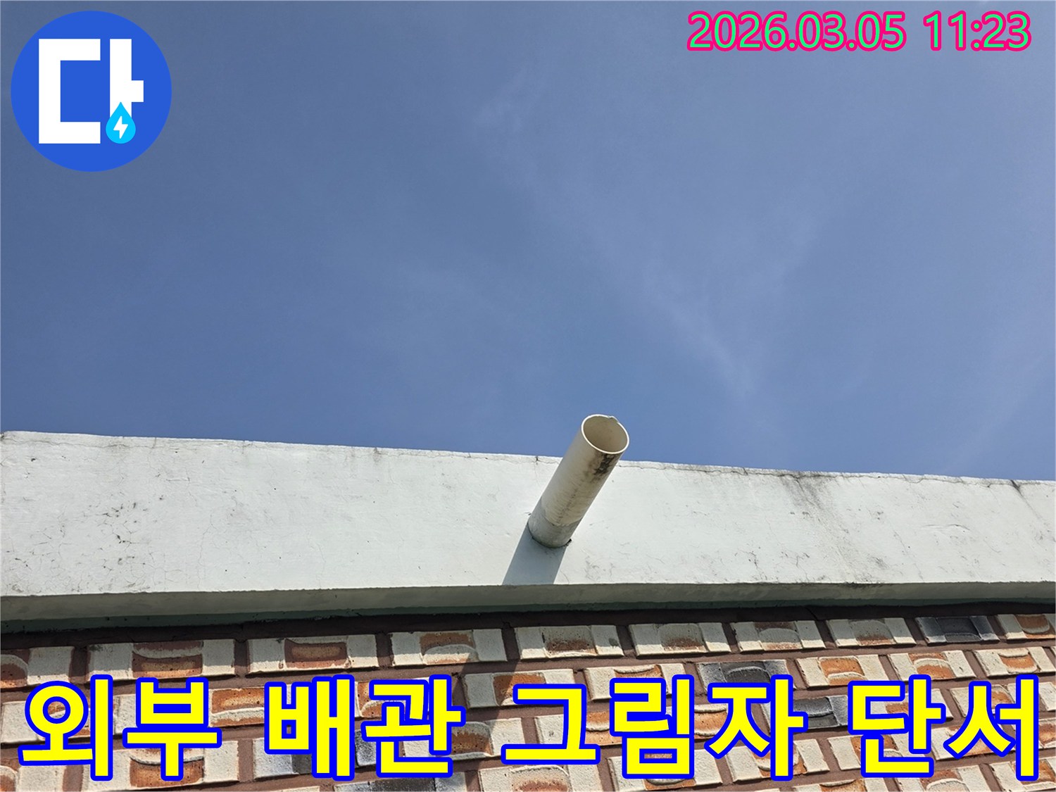 푸른-하늘-아래-건물-외벽에서-돌출된-배수관과-그-그림자를-통해-누수-단서를-찾는-사진입니다.