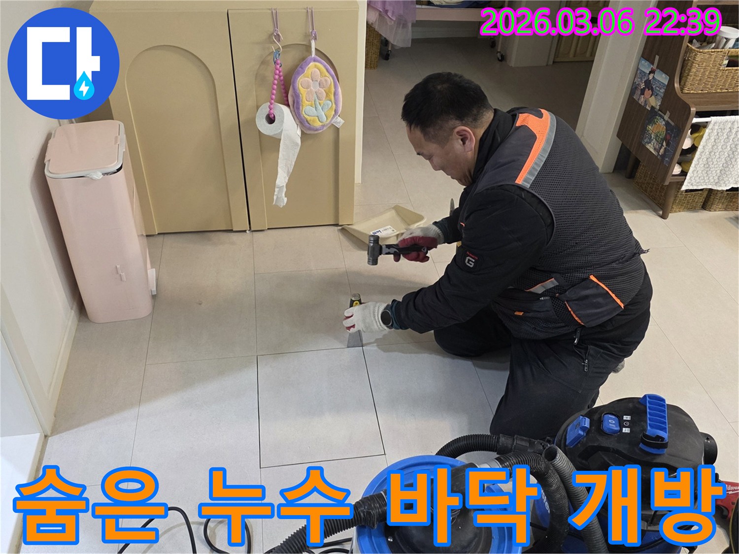 누수 전문가가-바닥 아래 숨겨진 배관을 점검하고자-타일 개방 작업을 진행하고 있습니다.