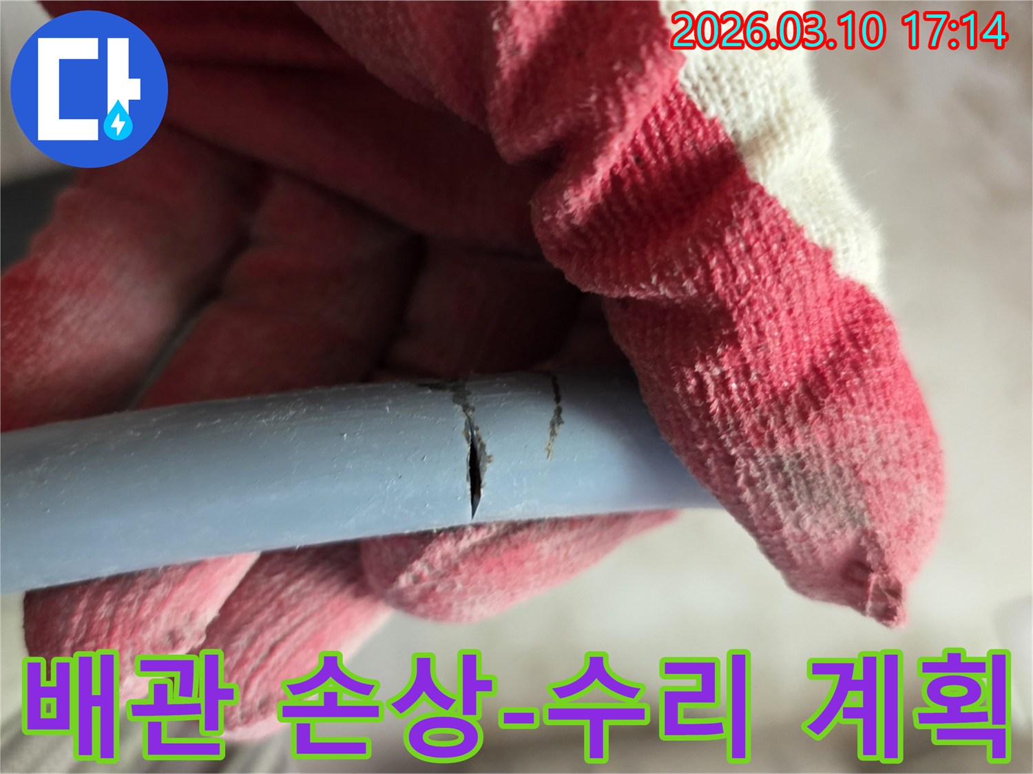 작업용 장갑을 낀 손이-손상된 수도관의 파열 부위를 가리키며-수리 계획을 세우고 있습니다