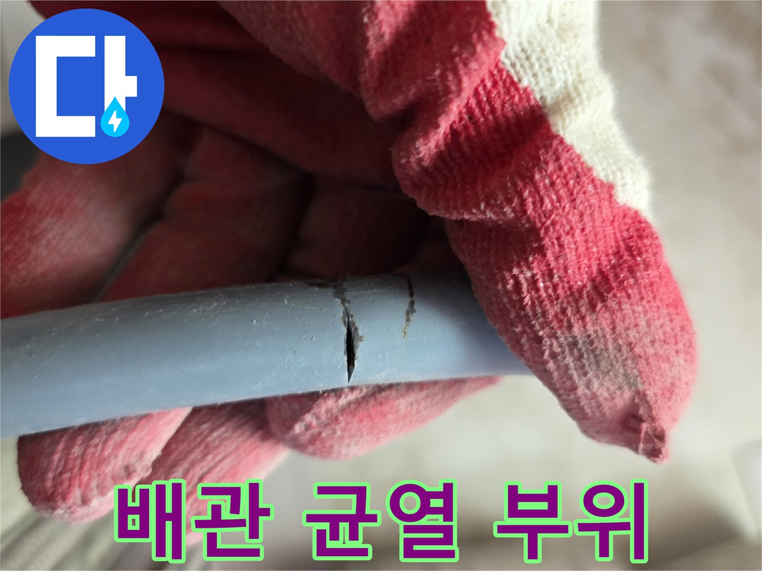 장갑을 낀 손이 잡고 있는 파란색 배관의 세로 균열 상태