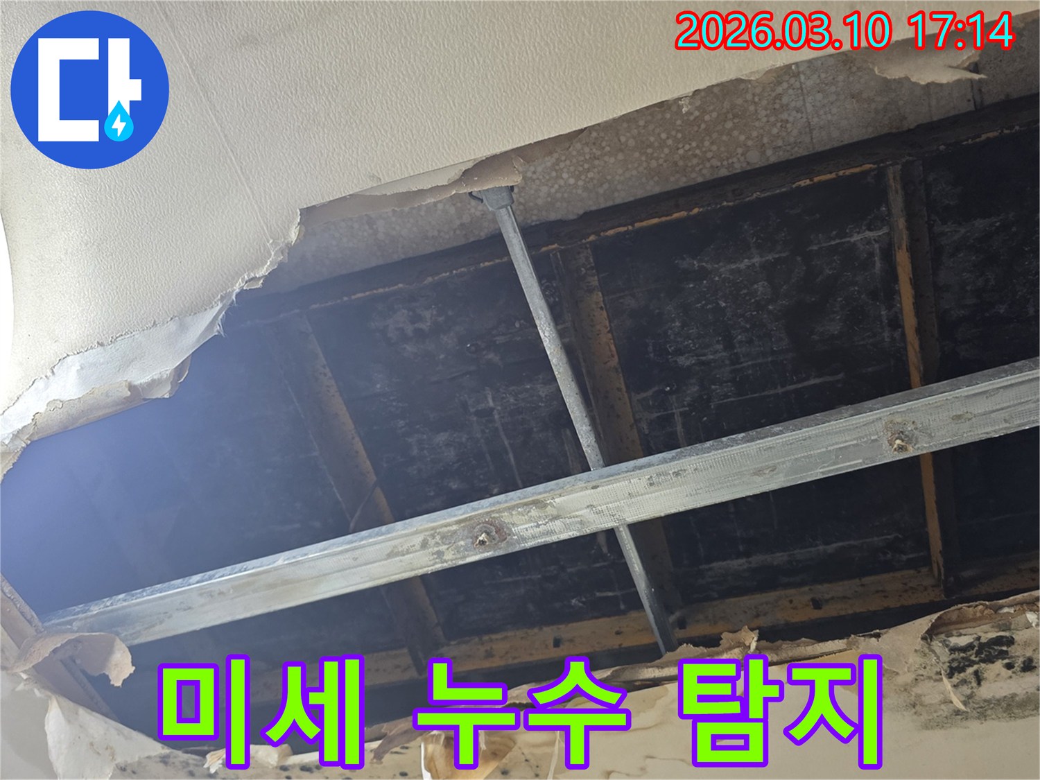 천장 마감재가 찢겨져 내부 구조물이 노출되고-물기로 인해 변색된 누수 현장의 모습입니다