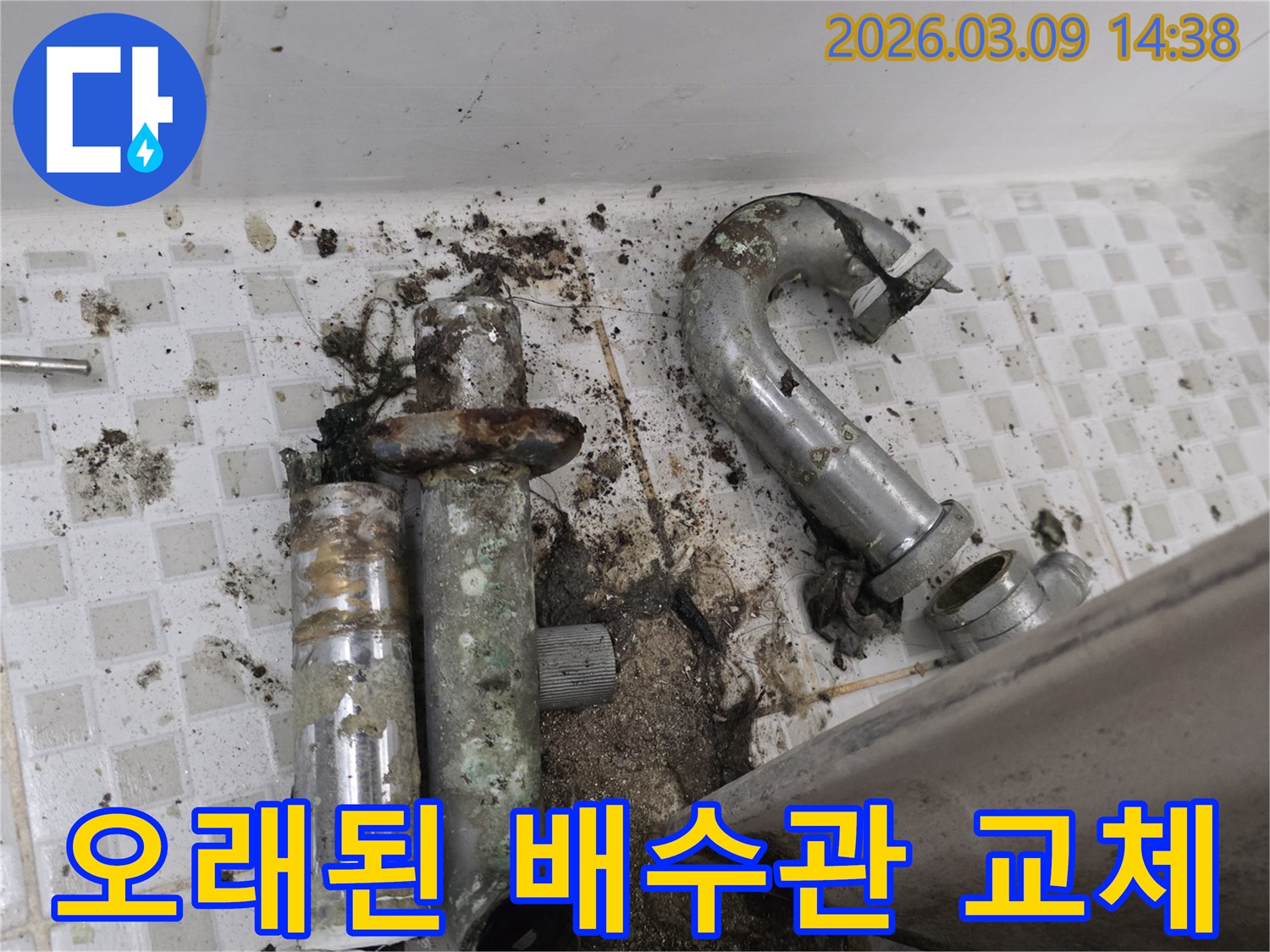 이 이미지는 노원구 공릉동 현장에서-오래되어 심하게 부식된 배수관과-그로 인해 오염된 바닥을 보여줍니다-교체 전의 모습입니다