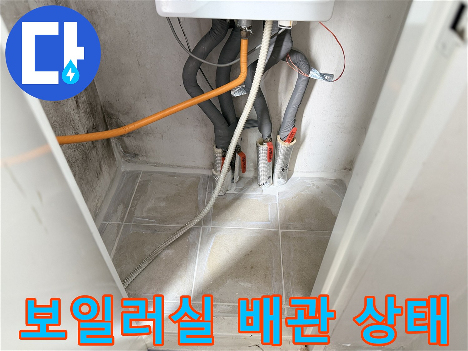 보일러실 하단에 연결된 굵은 회색 배관과 주황색 호스 현장 모습