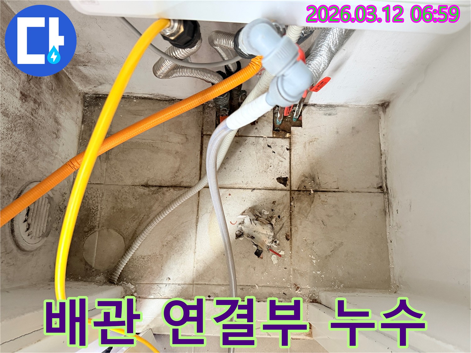 여러 배관들이-복잡하게 연결된 곳에서-바닥에 물기와-오염 흔적이 보이는-누수 현장 사진입니다.