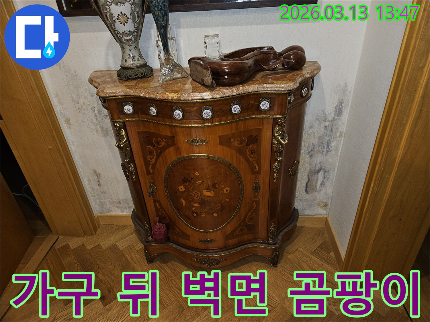 고급스러운 콘솔 가구 뒤-벽에 발생한-누수로 인한-벽지 변색과-곰팡이 흔적을 보여주는 사진
