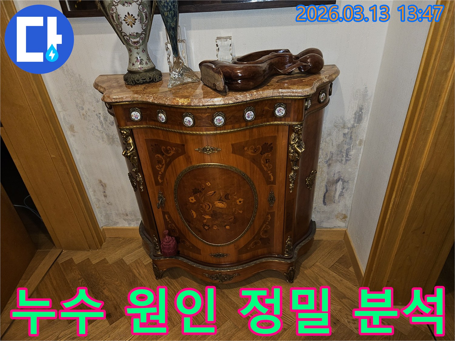 고급스러운 콘솔 가구 뒤-벽에 발생한-누수로 인한-벽지 변색과-곰팡이 흔적을 보여주는 사진