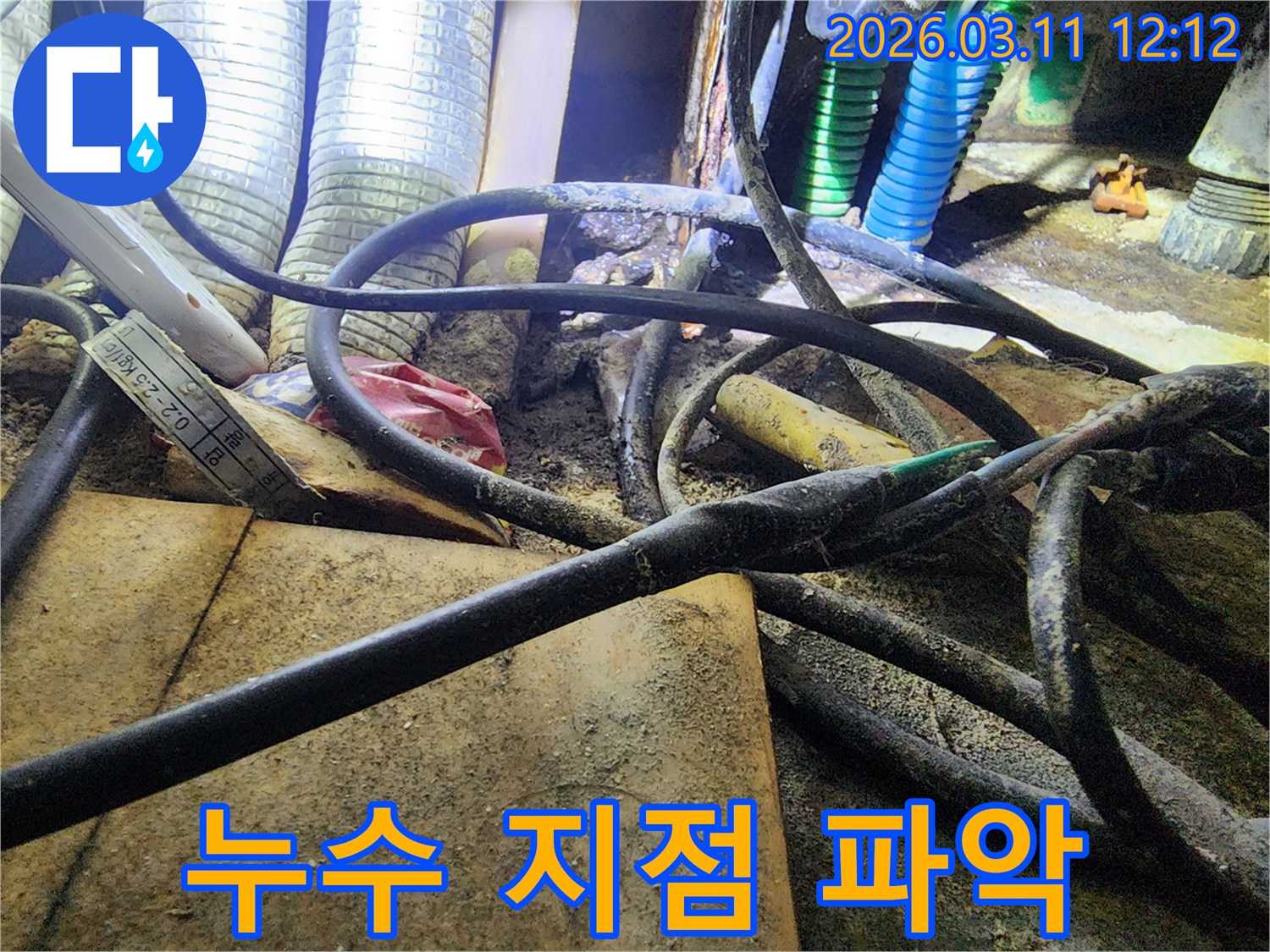 누수-공사 현장에서-복잡하게-얽힌-배관과-전선-사이의-오염된-모습을-담은-사진입니다.
