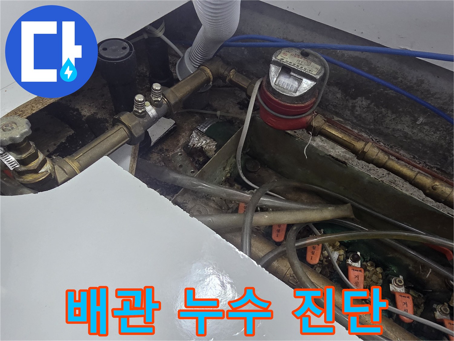 싱크대 하부 배관의 금속 연결 부위와 계량기 근접 촬영입니다.