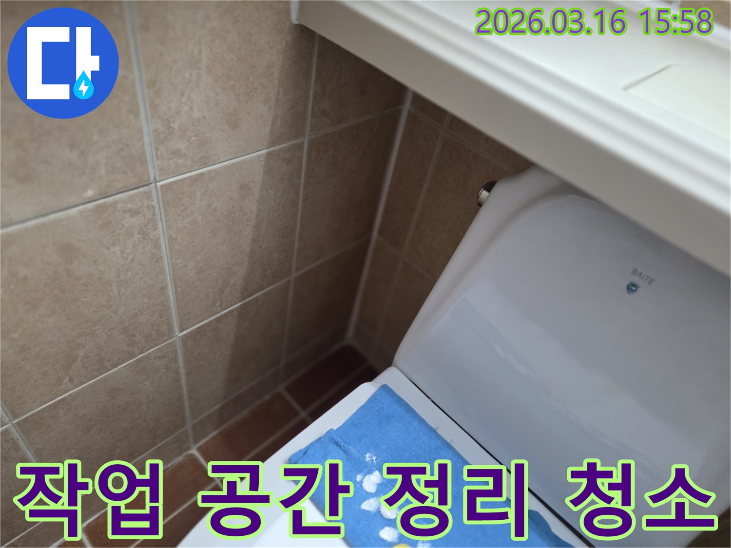 오산시 운암동의-한 욕실에서-변기 뒤편-벽면 타일의 젖음으로-누수 공사 완료 후-작업 공간을-깔끔하게 정리하고-청소하는 현장을-보여주는 사진입니다.