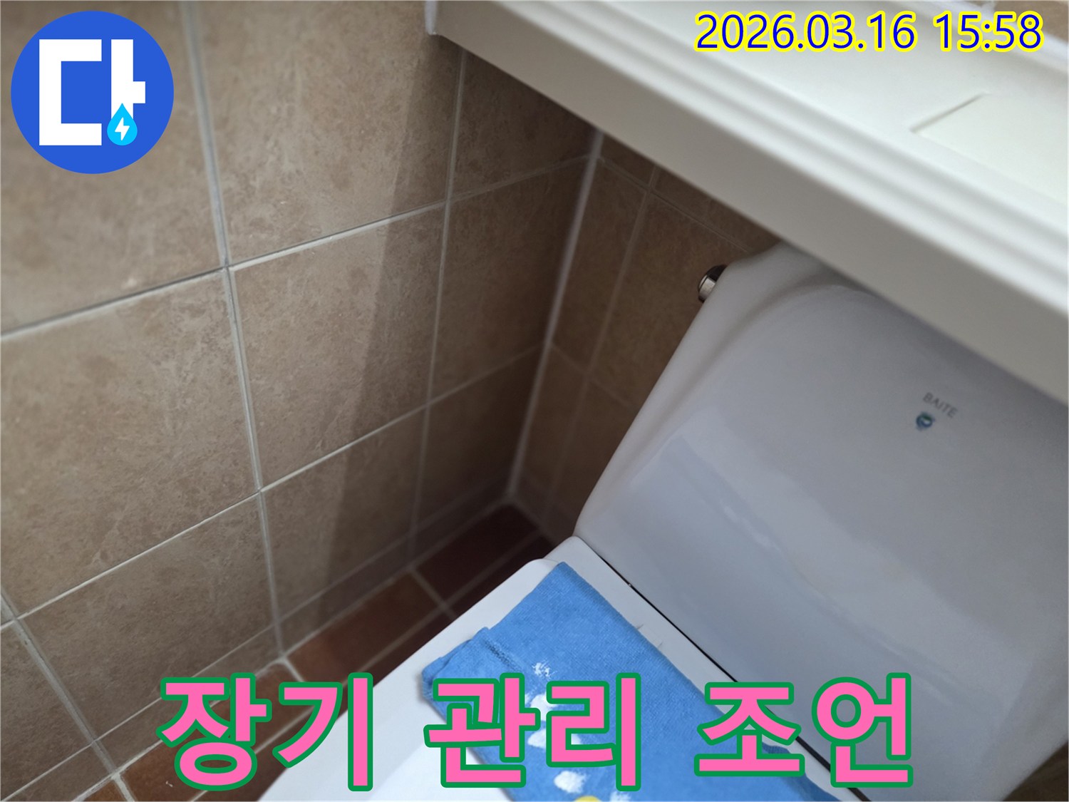 오산시 운암동의-한 욕실에서-변기 뒤편-벽면 타일의 젖음으로-누수 수리 후-장기적인 관리를 위한-조언을 제공하는-현장을 보여주는-사진입니다.