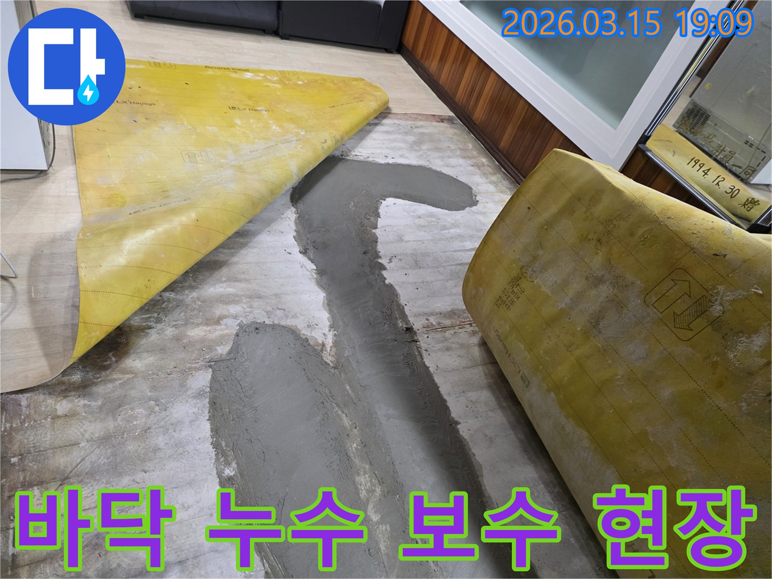 누수 공사 중 바닥을 보수하는 모습으로-새로운 시멘트 마감 작업이 진행되고 있습니다.