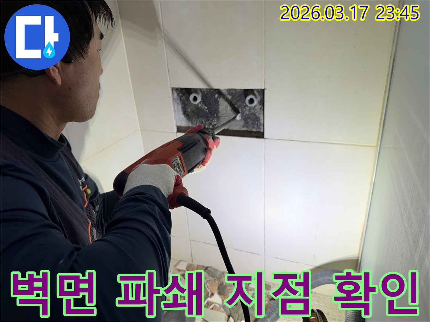 누수 전문가가 사무실 벽면 타일을 깨끗하게 파쇄하며-누수 원인인 배관의 누수 지점을 육안으로 확인하는 작업을 진행 중입니다.