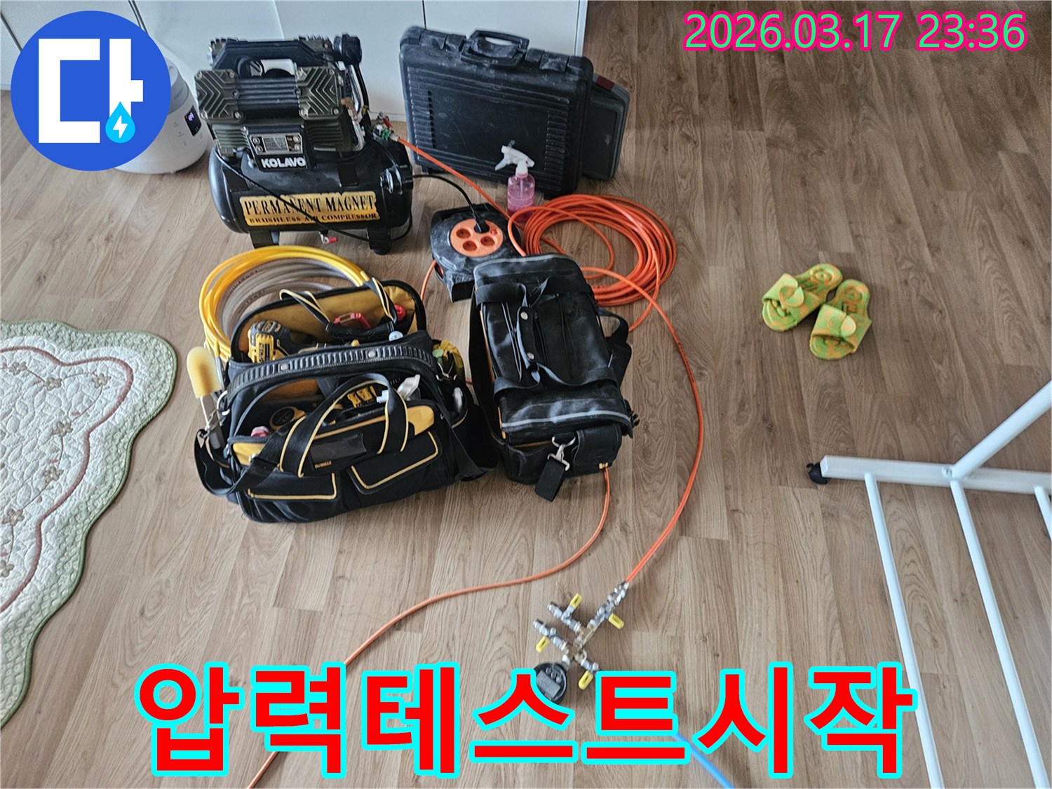 누수 탐지 전문가가 고객님 댁에 방문하여-배관 압력 테스트를 위한-콤프레셔와 게이지를 세팅하고 있습니다.