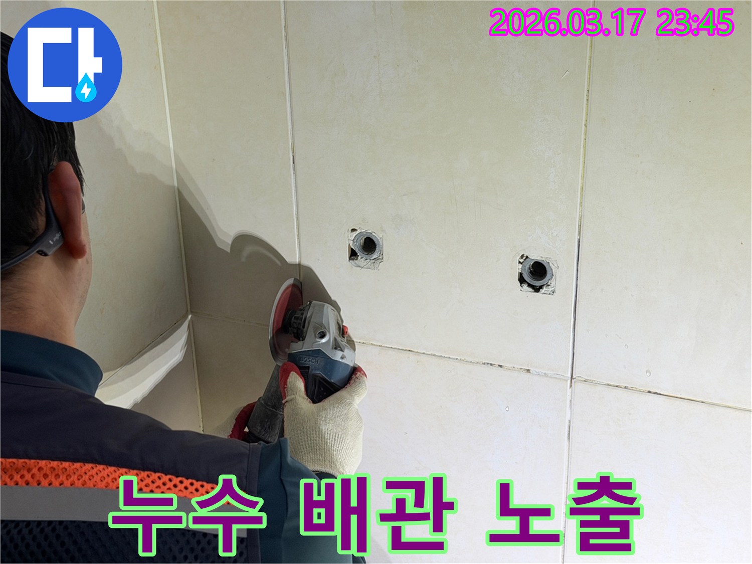 누수된 배관을-노출시키기 위해-전문가가-타일 벽면을-그라인더로-조심스럽게-커팅하고-있습니다