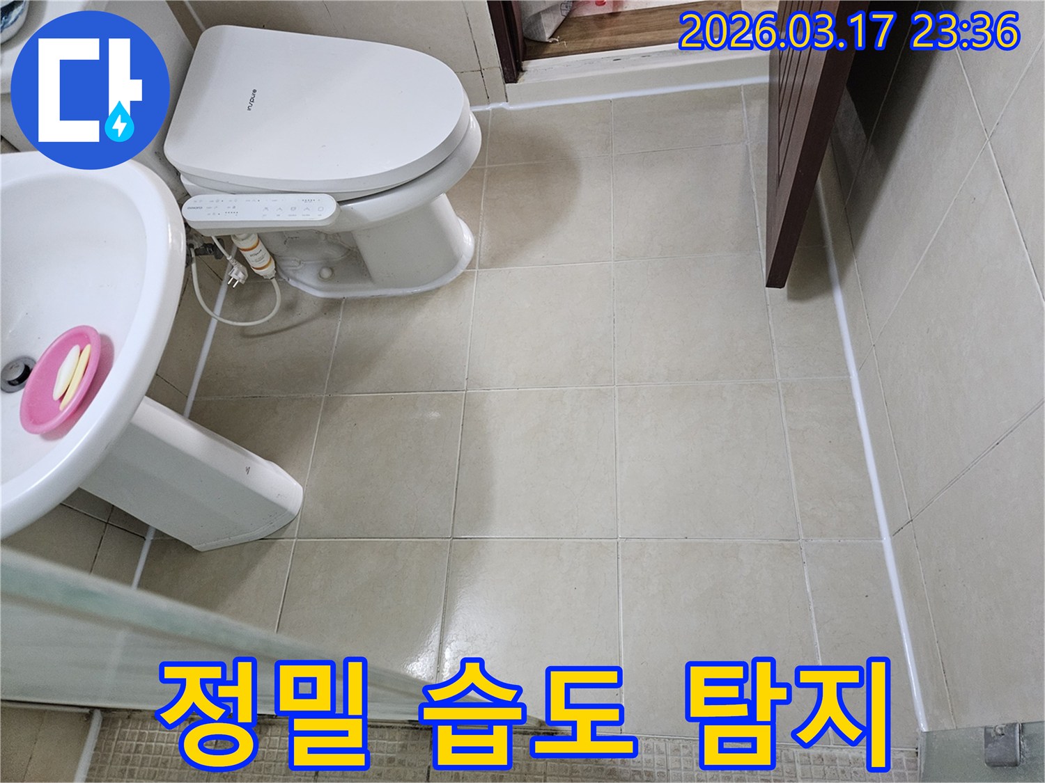 빌라 욕실 바닥 타일과 변기 주변에서-정밀 습도 측정기를 사용하여-육안으로 보이지 않는 숨겨진 습기를-탐지하는 모습입니다