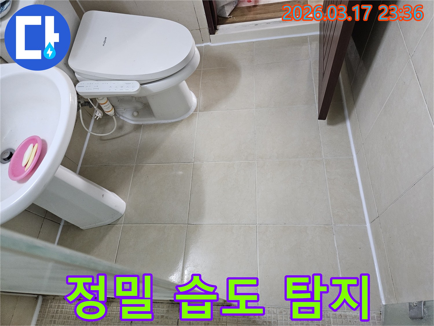 빌라 욕실 바닥 타일과 변기 주변에서-정밀 습도 측정기를 사용하여-육안으로 보이지 않는 숨겨진 습기를-탐지하는 모습입니다