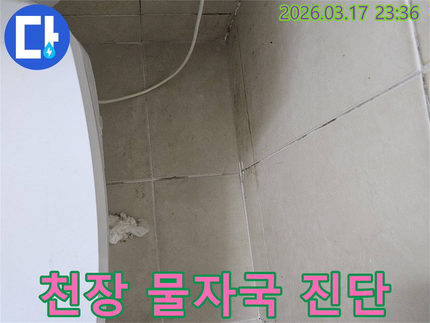 이 이미지는-천장-타일과-벽면-모서리에-나타난-물자국과-곰팡이를-보여주며-이는-상층부-또는-내부-배관의-누수로-인한-지속적인-습기-침투를-의미합니다