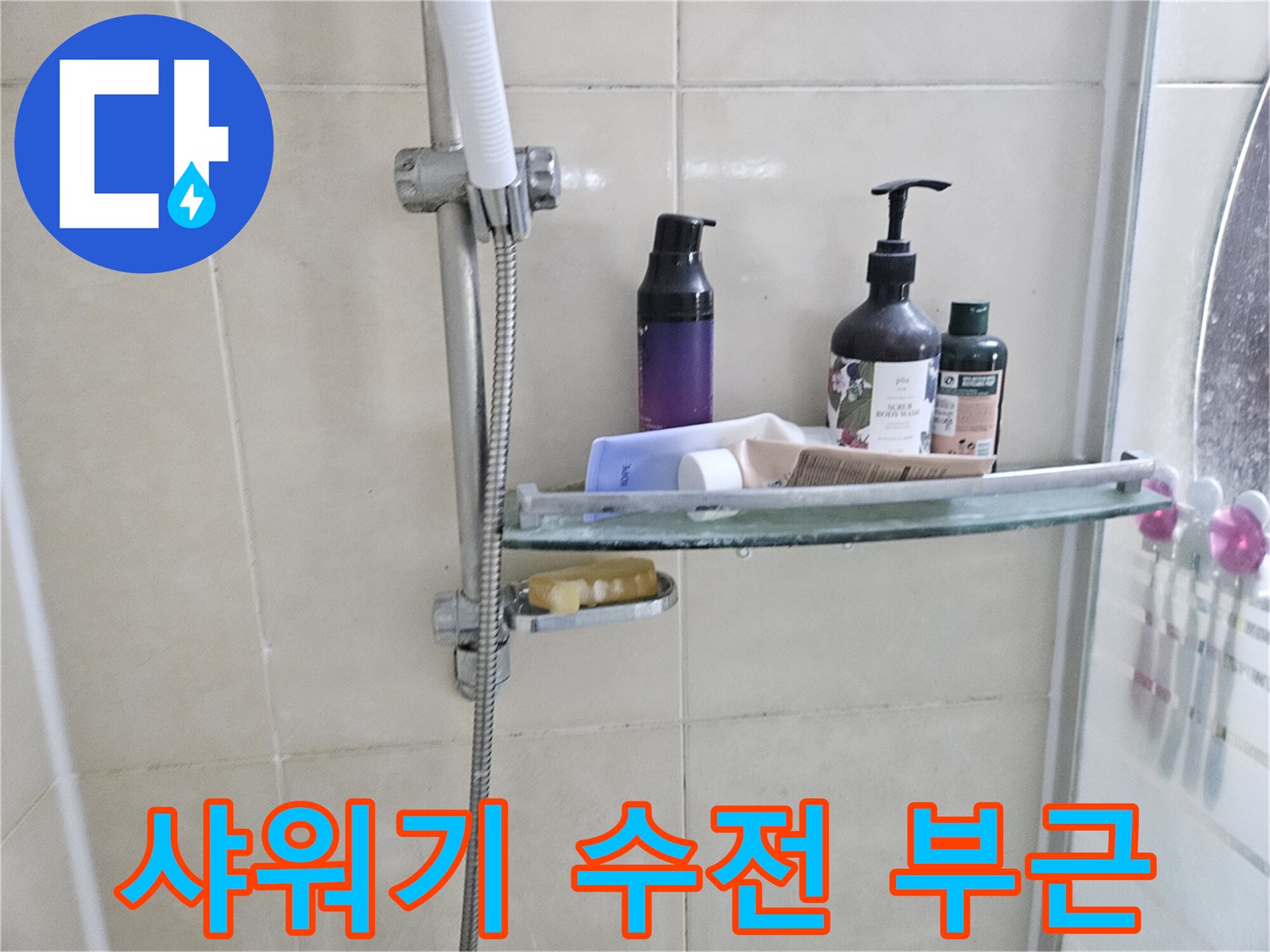 화장실 샤워기 수전과 선반이 설치된 타일 벽면 모습