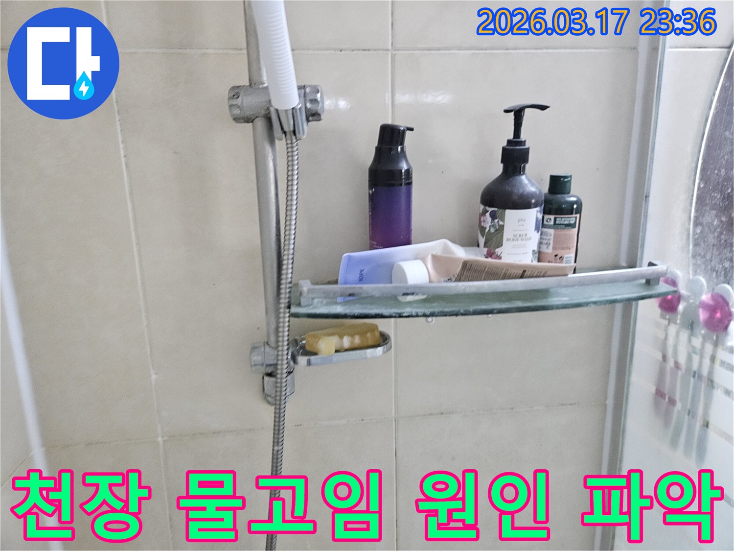 화장실 샤워기 옆-유리 선반에 맺힌 물방울은-천장 물고임의 간접적인 증거를 보여주는 이미지입니다