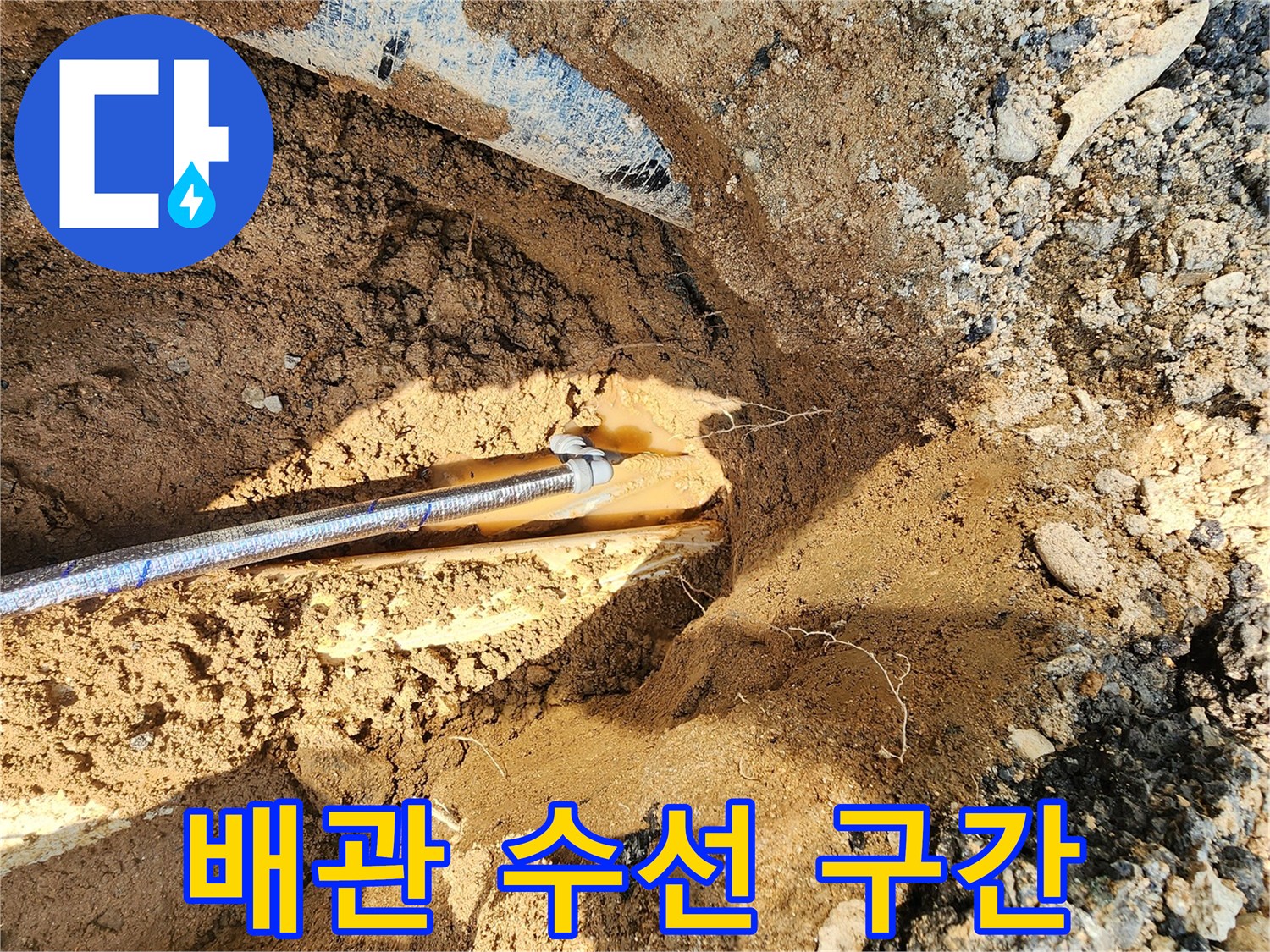 상수도 배관의 파손 부위를 확인하기 위해 흙을 파낸 현장 사진입니다.