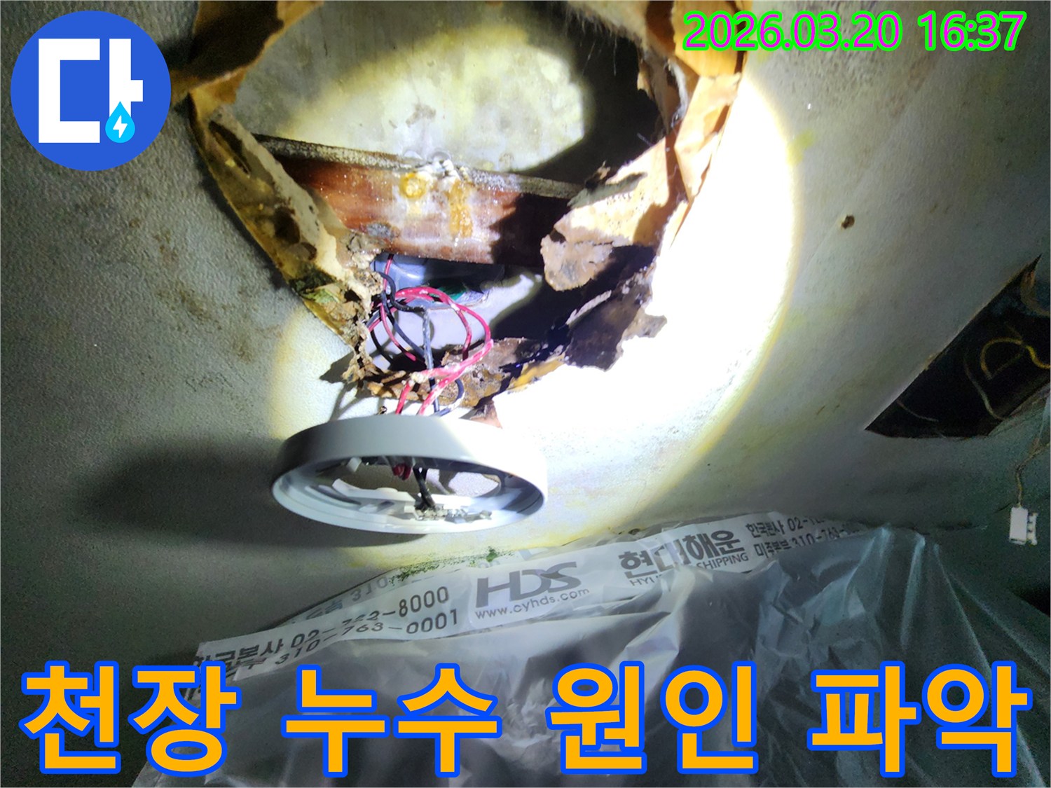 천장 누수-현장에서-손상된-천장 마감재와-노출된-배관을-조명으로-확인하며-피해 복구-계획을-세우는-모습입니다