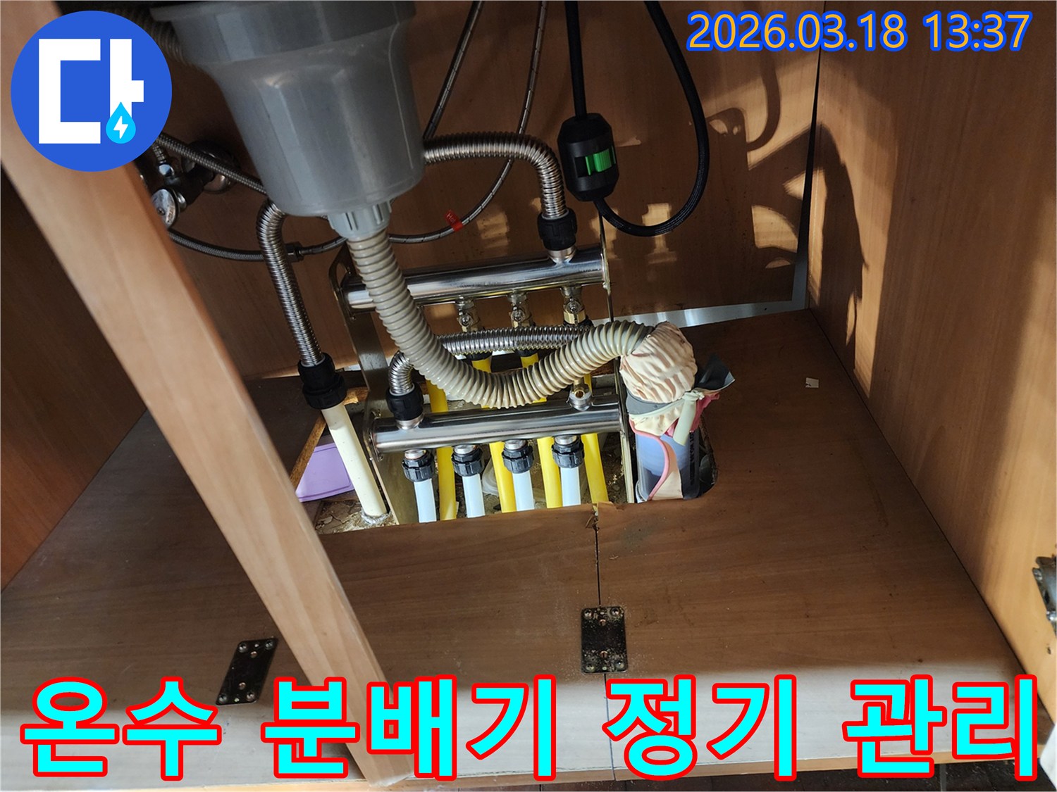 싱크대 하부장 내부의-온수 분배기를-정기적으로 점검하여-누수를 예방하고-효율을 유지하는-모습입니다