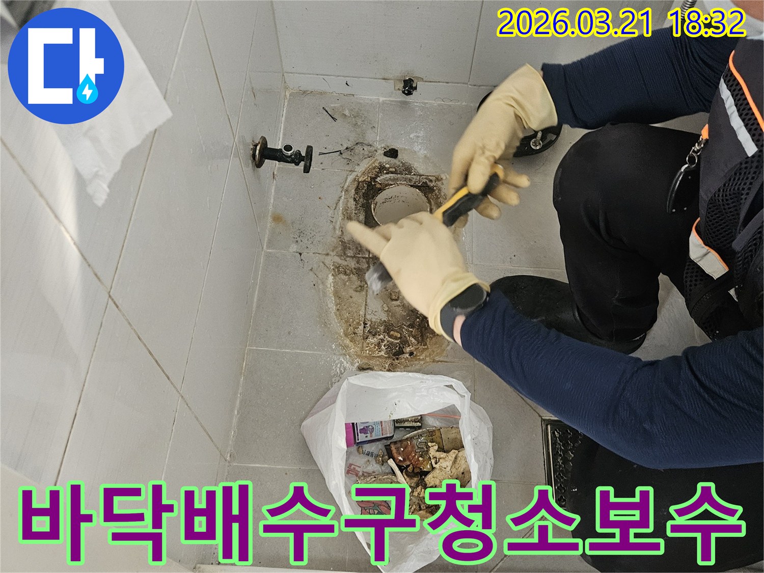 누수 엔지니어가-화장실 변기 하부의-바닥 배수구 주변에 쌓인-오염물질을-제거하며-청소 및 보수 작업을-준비하고 있습니다