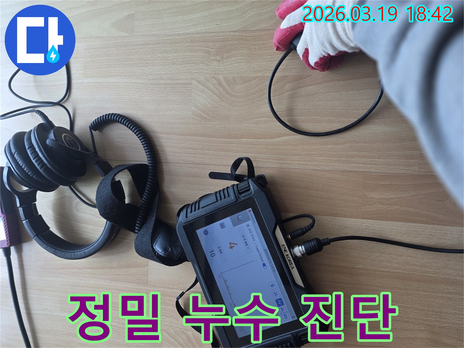 숙련된 엔지니어가-누수 탐지 장비를 활용하여-바닥에서 발생하는-미세한 누수 소리를-집중적으로 듣고 분석하는 장면입니다