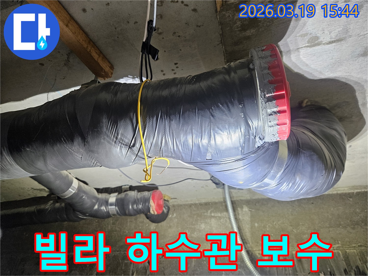 천장에 설치된 검은색 단열재로 감싸진 굵은 하수관과-그 옆으로 연결된 회색 파이프들이 보입니다