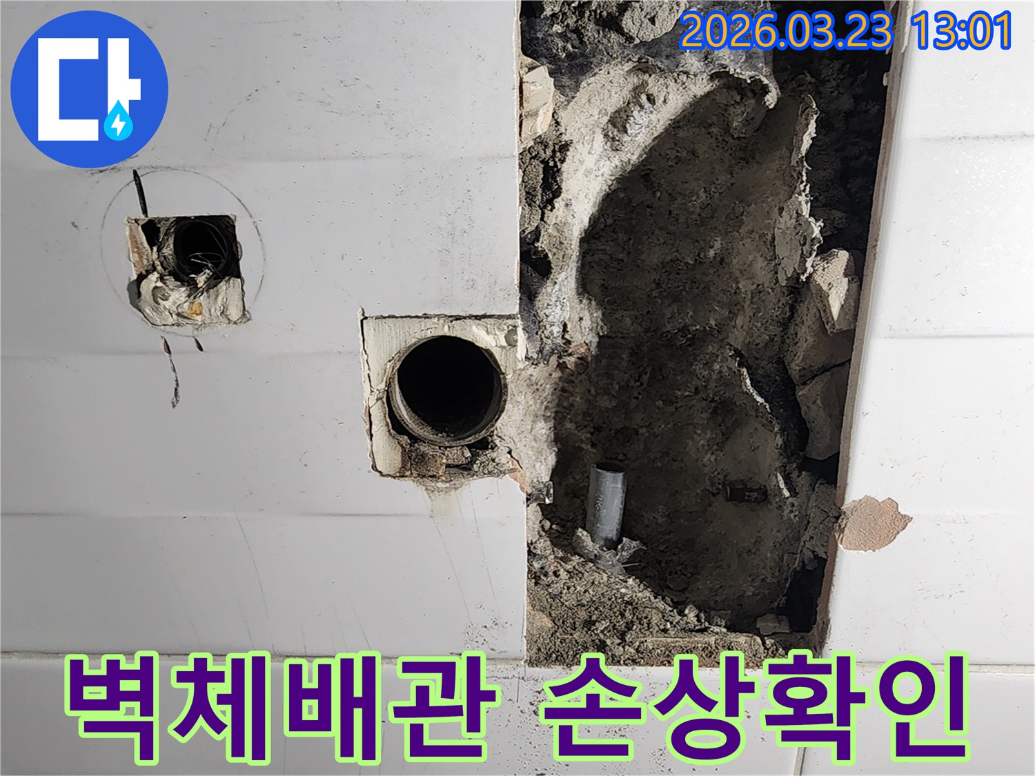 누수로 인해 벽면이 파손된 현장에서-노출된 배관의 상태를 면밀히 검토하며-손상 부위를 특정하는 작업 모습