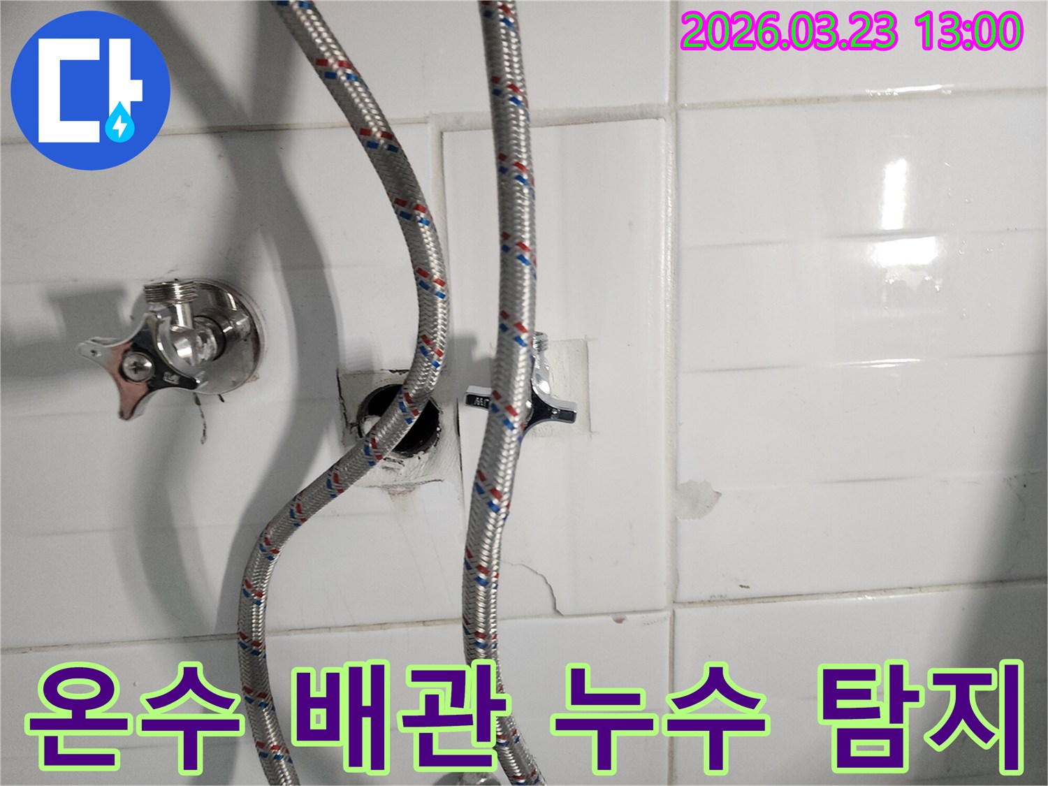주택 욕실에서 온수 배관 누수를 탐지하고 보수하는 작업 현장입니다-노출된 배관과 주변의 물기가 보입니다