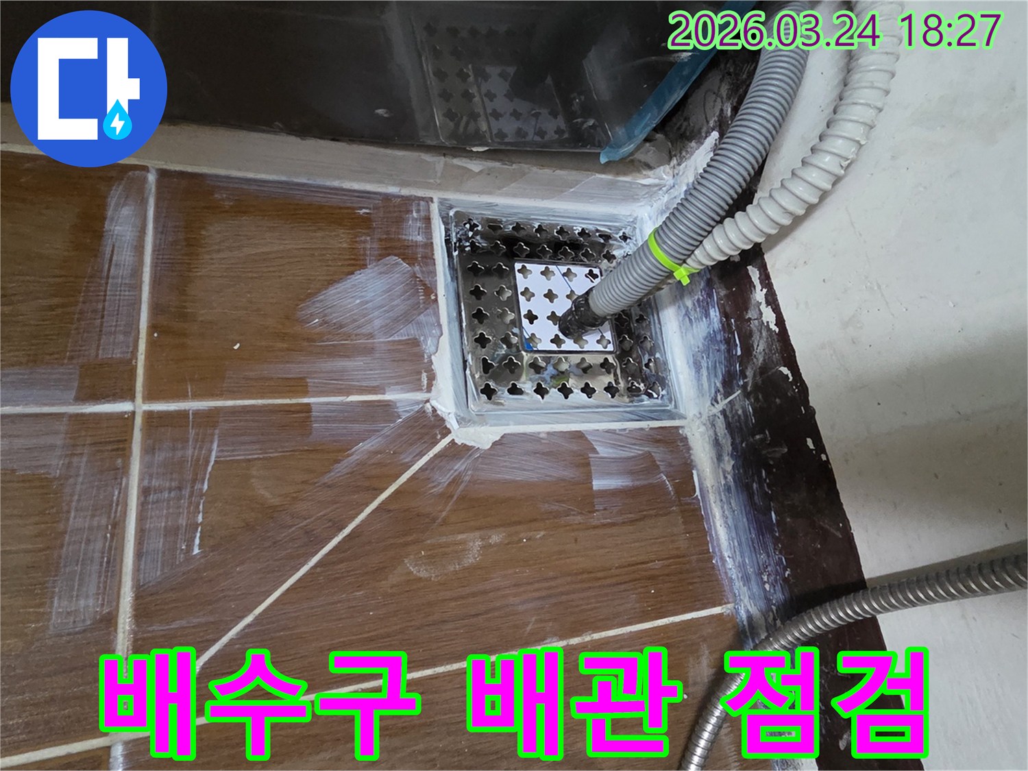 이 이미지는-동두천에서 진행된-누수공사 현장에서-배수구 배관의-상태를 면밀히-점검하는 모습을-담고 있습니다