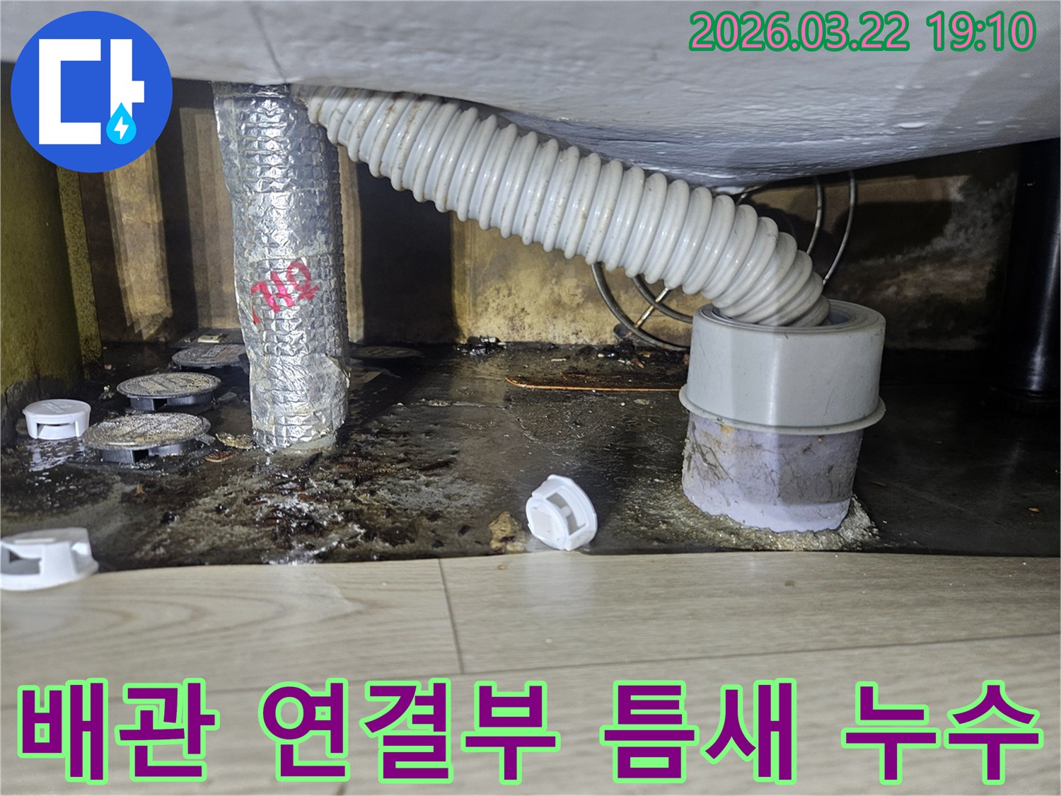 배관 연결 부위의 틈새에서-누수가 발생하여-바닥이 오염된 현장을-전문가가 보수하는 모습