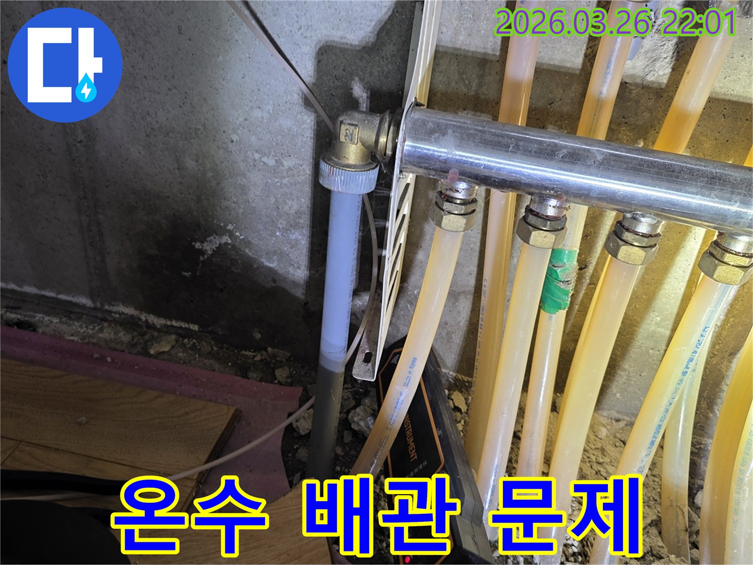 이 이미지는-온수 배관 누수-탐지 현장에서-젖은 벽면과-배관-그리고-탐지 장비를-보여줍니다.