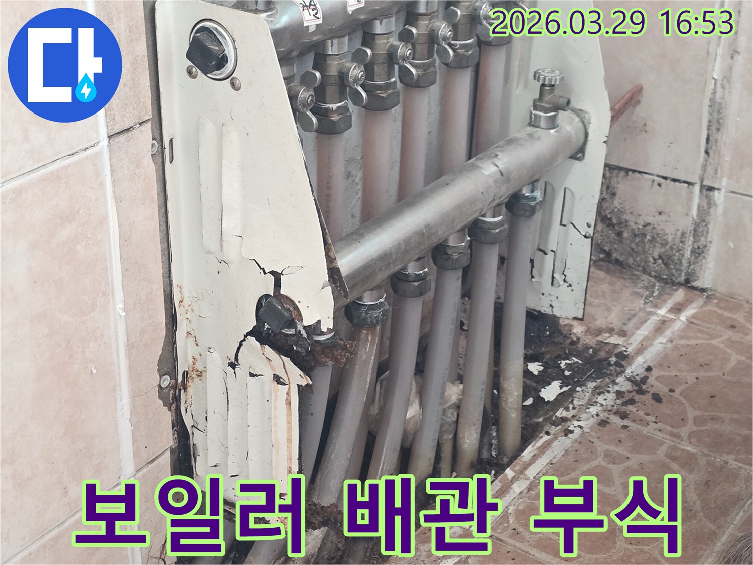 이 이미지는 낡고 부식되어 누수가 발생한 보일러 분배기 주변의 배관 상태를 상세히 보여줍니다.