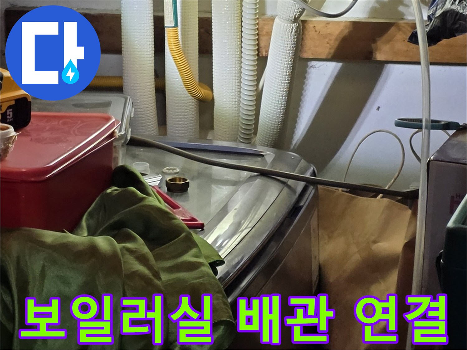 보일러 아래쪽-여러 개의 배관과 연결 호스가 복잡하게 얽힌 모습