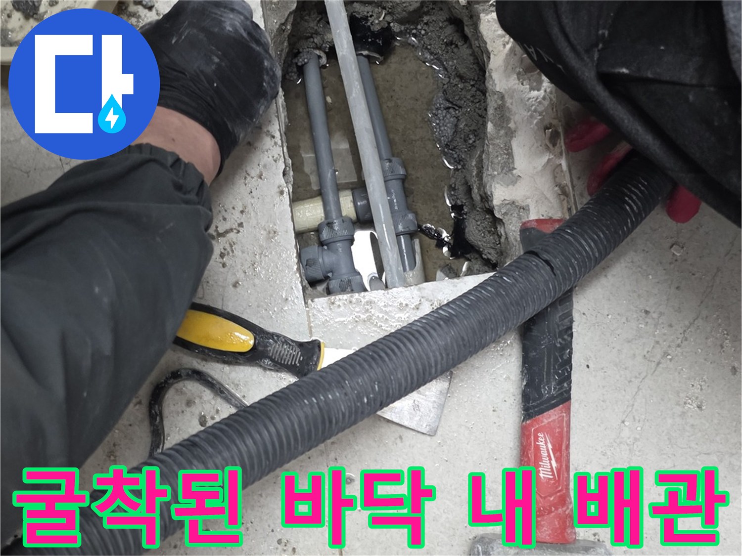 싱크대 하단 굴착 부위에 드러난 회색 PVC 배관과 작업 도구