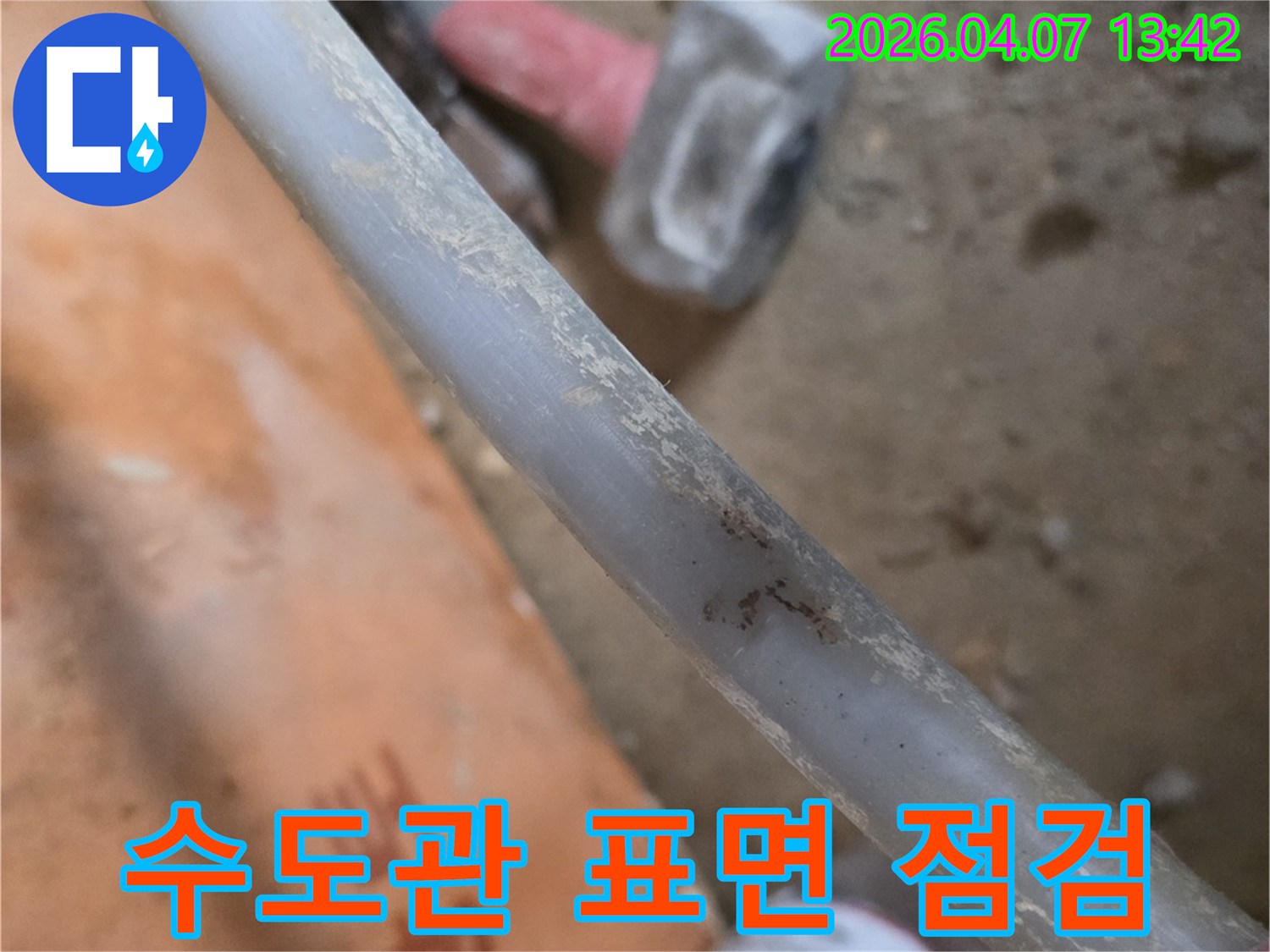 누수-현장에서-수도관의-표면-오염과-손상-여부를-정밀하게-점검하는-엔지니어의-모습을-담은-사진입니다.