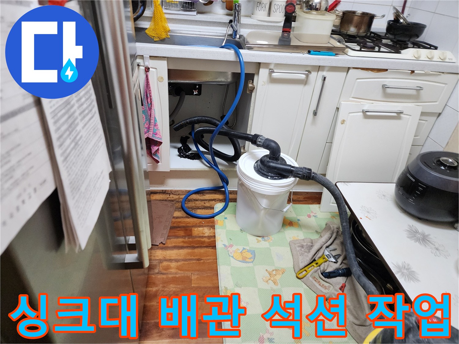 주방 싱크대 하부장 아래에서 진행되는 배관 석션 장비 사용 모습