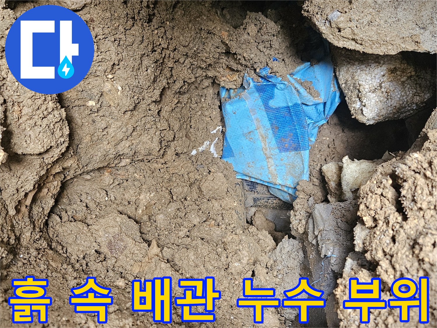 파헤쳐진 흙 속에 드러난 파란색 천과 매립된 배관 주변의 습한 상태