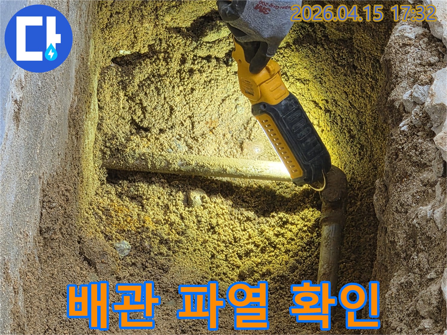전문가가-땅속-배관의-파열-지점을-손전등으로-비춰-육안으로-확인하고-있는-긴급-누수-현장입니다.