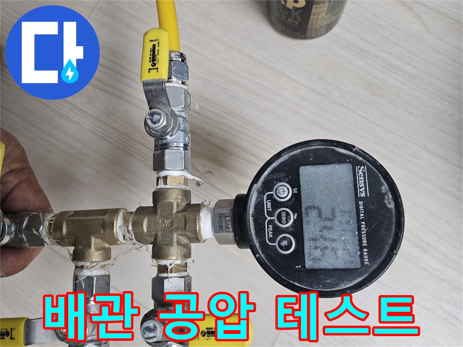 황동 재질의 분기 밸브와 디지털 압력계가 연결된 배관 점검 장비 구성입니다.