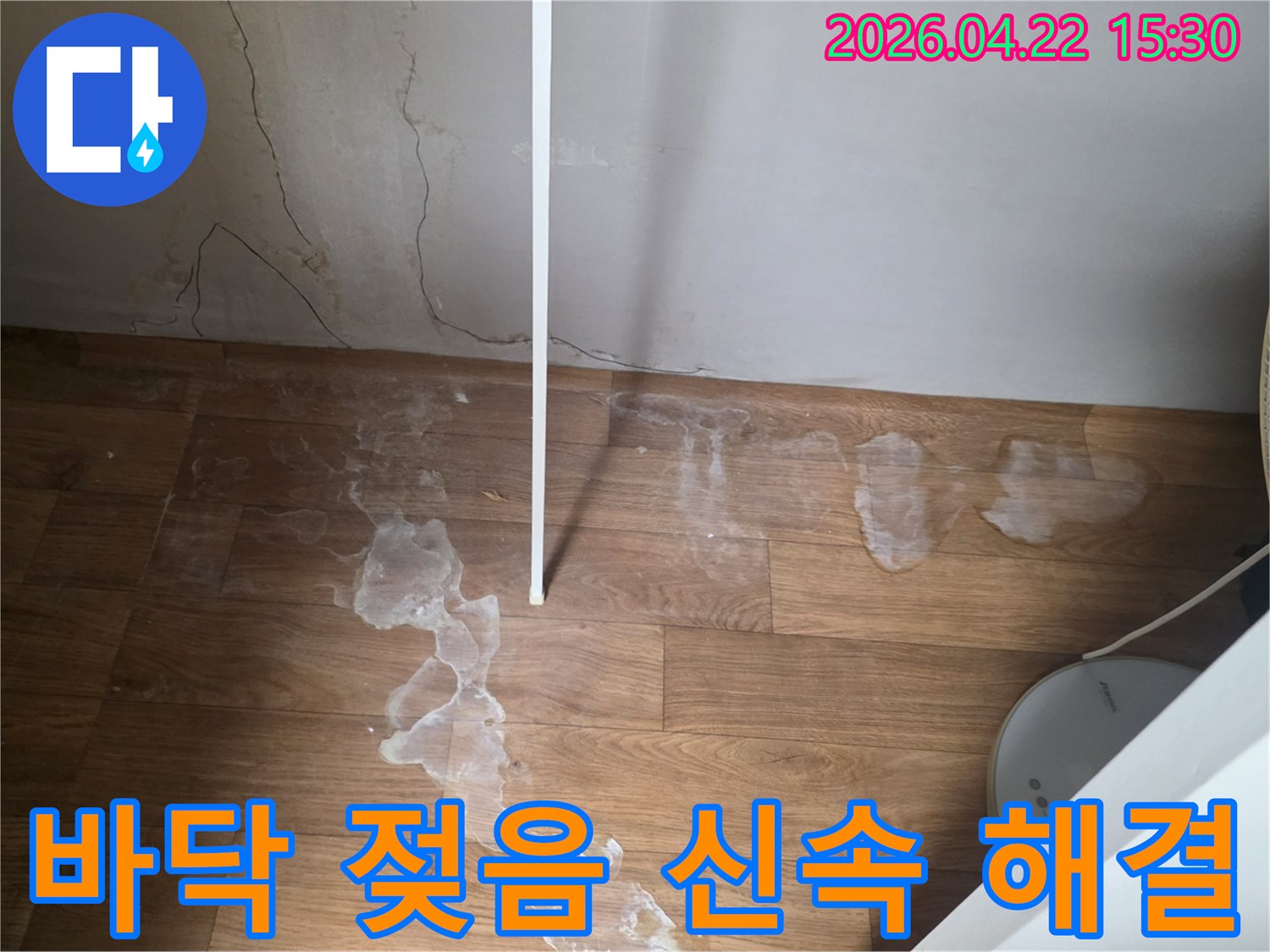 이 사진은 바닥에 생긴 물자국과 벽면의 습기 흔적을 보여주며-누수 엔지니어가 현장 점검을 진행하고 있습니다