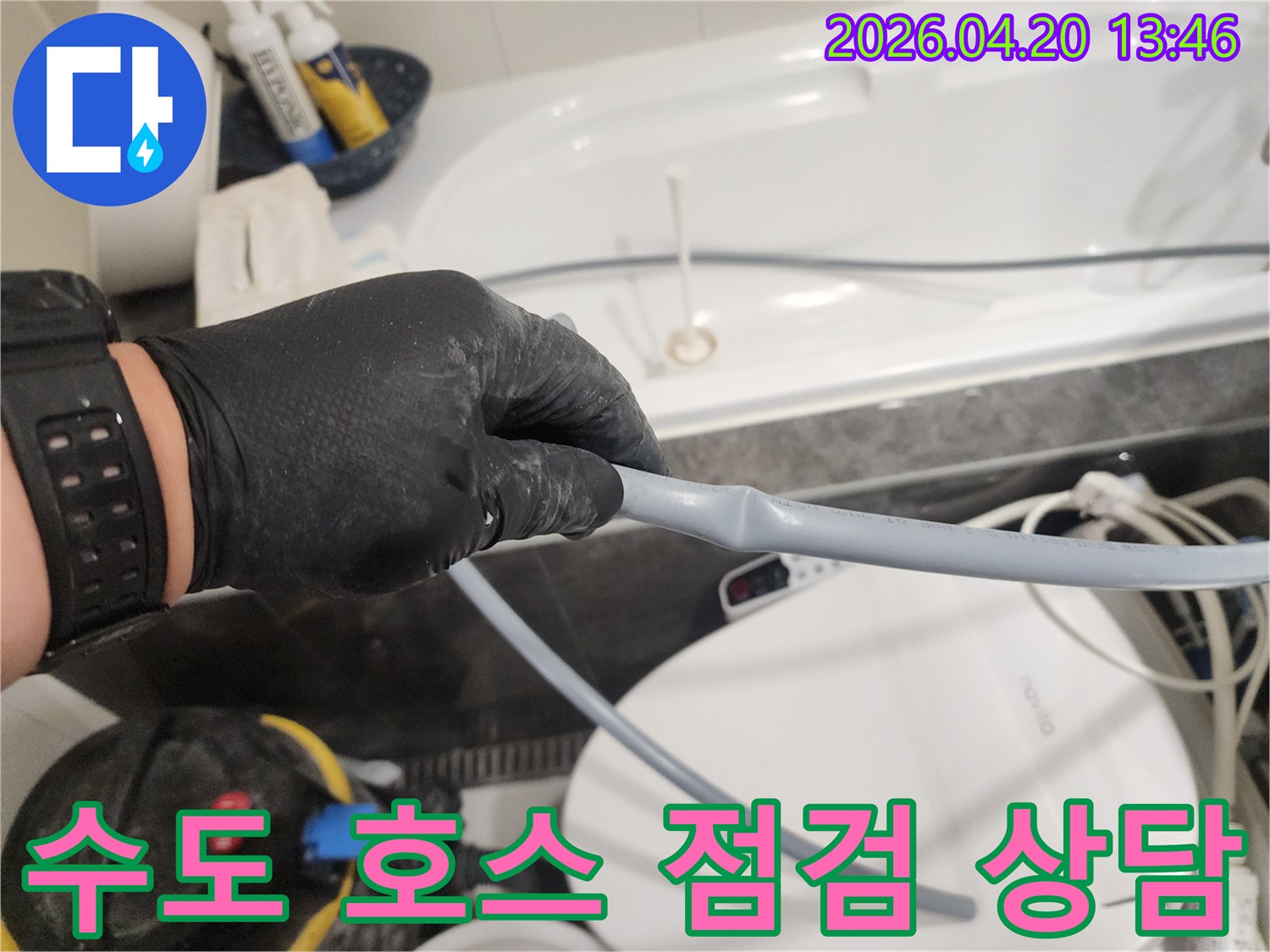누수 전문 엔지니어가 검은 장갑을 끼고-화장실 수도 호스의 상태를 점검하며-교체 필요성에 대해 상담하고 있습니다.
