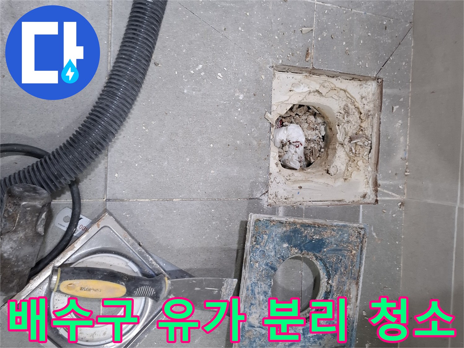 욕실 바닥 배수구의 유가를 분리하여-내부에 쌓인 이물질을 청소하고 배관 상태를 점검하는 모습입니다