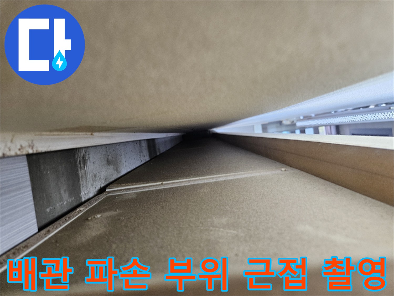 싱크대 하부 배관의 찌그러진 부분과 손상된 지점을 보여주는 사진입니다.