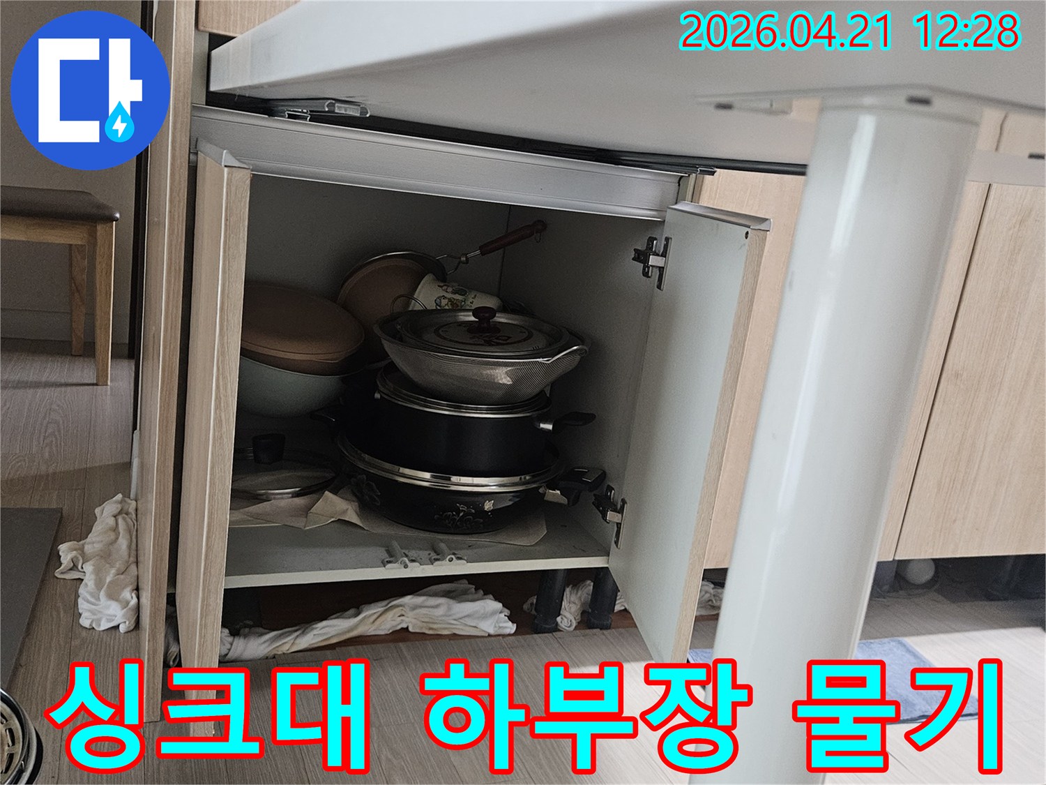 싱크대 하부장 안쪽에서 발견된-물기로 인한 얼룩과 젖은 수납 공간-배관 문제로 인한 누수 현상