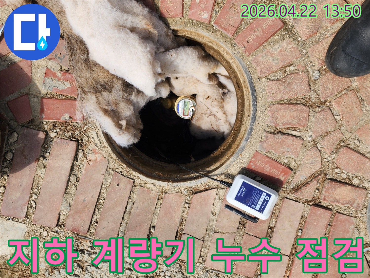 보온재로 덮인-수도 계량기 옆에-누수 탐지 장비가 작동 중인 현장입니다.
